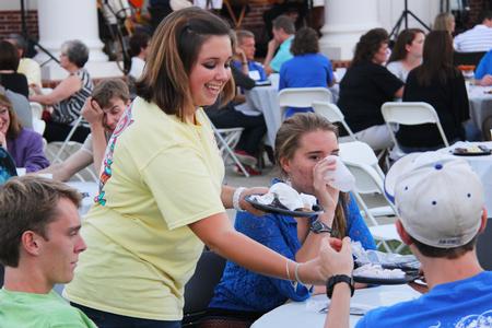 Bailey Howell, freshman nursing major, takes up plates from a family at the Chi Omega barbecue fundraiser for Make a Wish Foundation, which took place during Family Weekend. - Photo by Matt McDaniel