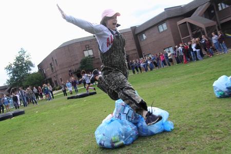 Mallory Lamm, freshman social work major, jumps over the recycling bags in the obstacle course during the DF Olympics in the Heritage Complex. - Photo by Matt McDaniel