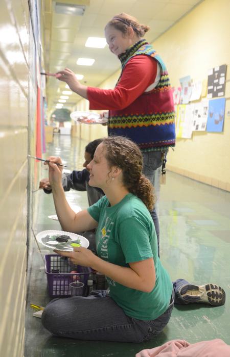 Tommy Woods, Caitlyn Miller and Betsy Marsch, senior art majors, work together to touch up a mural at Pope Elementary School for Campus & Community: A Day of Remembrance and Service.  - Photo by Amanda Rohde