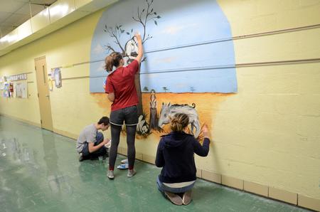 Josh Bullis, senior art major, touches up a mural with Kristen Witham, and Sierra Owens-Hughes, junior art majors, at Pope Elementary School as a part of Campus & Community: A Day of Remembrance and Service. - Photo by Amanda Rohde