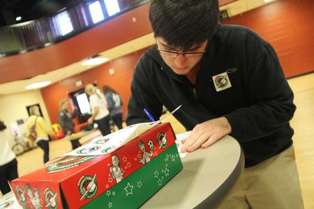 Clayton Stewart, freshman, writes a letter to a child in need for Operation Christmas Child as part of Campus and Community Day. - Photo by Matt McDaniel
