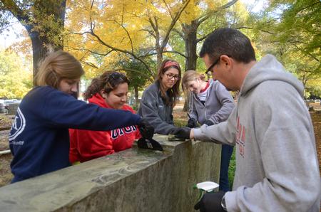Members of Union's Phi Alpha Theta chapter and history department scrub moss off a tombstone at Jackson's Historic Hollywood Cemetery during Campus and Community: A Day of Remembrance and Service. - Photo by Jacob Moore