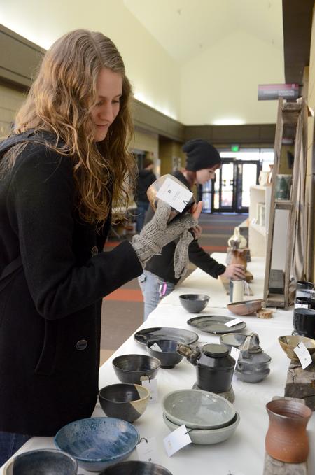 Lindsey Howerton, senior art therapy major, admires a handmade cup at the annual Christmas Pottery Sale in the Student Union Building. - Photo by Amanda Rohde