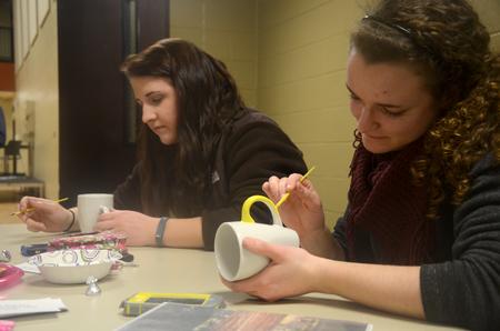 Rebecca Shamblin, left, freshman family studies major, decorates a mug next to Lauren Bone, sophomore psychology major, in support of World Vision International during Residence Life's Mugs & Kisses event at the Bowld Student Commons. - Photo by MiKalla Cotton