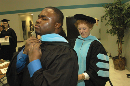 Education professor Carrie Whaley helped M.Ed. graduate Everett Singleton make final adjustments to his graduation robe while waiting for the processional to begin. - Photo by Jim Veneman