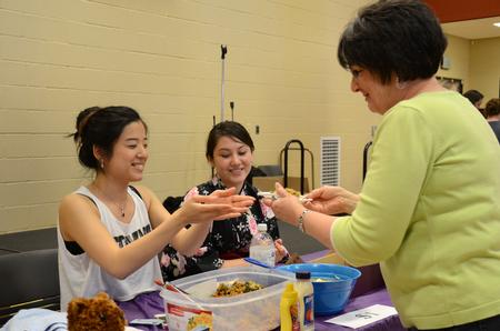 Two Japanese students share their snacks with a visitor at the International Food Fair in the Bowld Student Commons. - Photo by MiKalla Cotton