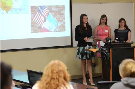 Holly Harris, senior tesl major, presents her research to faculty, staff, and students during the Scholarship Symposium. Harris and fellow senior tesl majors Anna Lewis (left) and Kaitlin Nonweiler presented on the "Impacts and Effects of Education Policy on Ethnolinguistic Minority Groups." - Photo by Anne Richoux