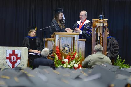 Holly Harris, senior class president, presents David S. Dockery a symbol of the senior class gift of a memorial garden during Union University's 189th Spring Commencement. - Photo by Meg Rushing
