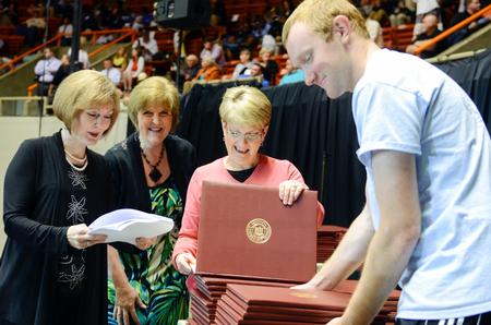 Michael Adkisson, right, junior business administration major, helps organize degrees while Alice Ferrar, Anita Todd and Susan Hopper double check the order of all 630 diplomas prior to the beginning of Spring Commencement. - Photo by Kathleen Murray