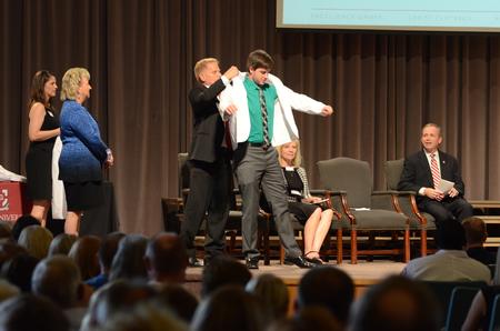 Randall Elrod, pharmacy student, receives his white coat from George A. DeMaagd, associate dean of the School of Pharmacy, at the White Coat Ceremony in the G.M. Savage Memorial Chapel. - Photo by MiKalla Cotton