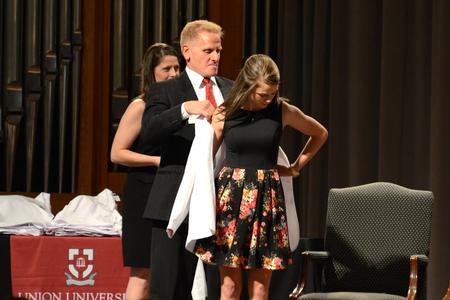 Class of 2018 pharmacy student, Anna Coln, receives her white coat at the White Coat Ceremony in the G.M. Savage Memorial Chapel. - Photo by Meg Rushing