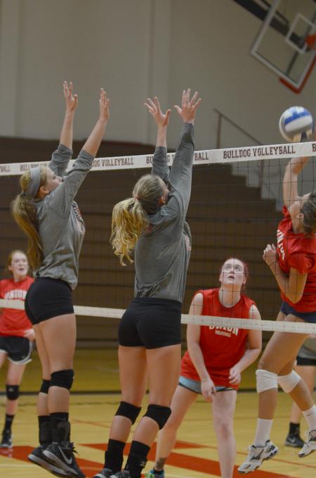 Kristin Cook, junior biology major, and Hannah Huguley, sophomore family studies major, block the incoming spike at the alumni volleyball game. - Photo by Emily Stookey