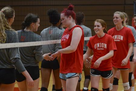 Union alumnae, Shelby Swink, Jami Humphries and Amanda Coyle, congratulate the current team on their win at the alumni volleyball game in the Fred DeLay Gymnasium. - Photo by Emily Stookey