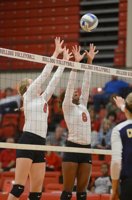 Mallory Baker and Deja Moorer jump to block the incoming volleyball during their game against Mississippi College. - Photo by Emily Stookey