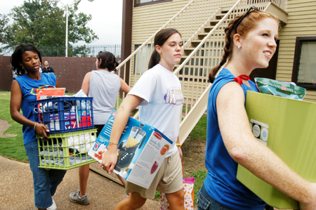 SAC members Miranda Wells (left) & Melody Pickerill (right) help freshman Lindsey Wallach haul her belongings into her new room during Freshmen Move-In. - Photo by Kristen Hiller
