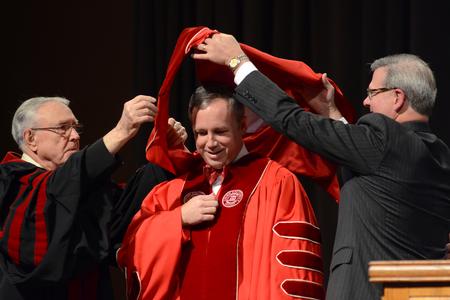 Hyran Barefoot, left, Union University's 14th president, and Norman Hill, right, Board of Trustees Chair, aid in the hooding process during Dub Oliver's presidential inauguration.  - Photo by Emily Stookey
