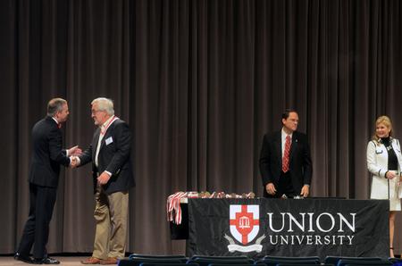 Dub Oliver, president of the university, congratulates members of the Class of '65 as they are recognized onstage in chapel. - Photo by Amanda Rohde