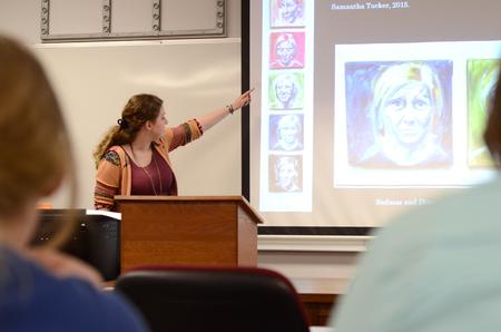 Samantha Tucker, junior art major, discusses her work during the art section of the Scholarship Symposium, where students present research and projects from the semester. - Photo by MiKalla Cotton