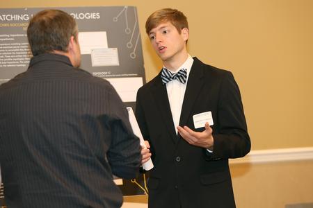 Chris Boccarossa, junior engineering major, explains his poster at the Scholarship Symposium poster sessions in the Grant Events Center.  - Photo by Kristi McMurry Woody