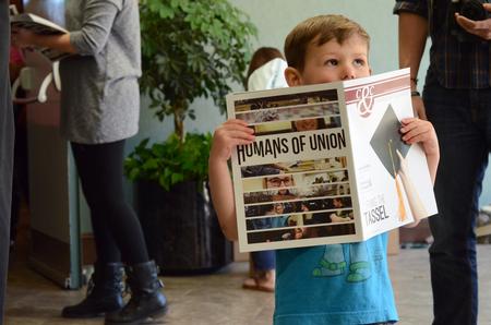 Finley Bredow, son of the resident director of the male quads, holds a Cardinal & Cream Spring 2015 magazine as students and faculty and staff proceed out of Awards Day Chapel. - Photo by MiKalla Cotton