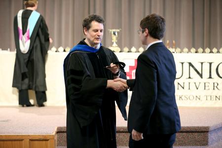 Jan Wilms, professor of computer science and department chair, presents Stephen Clement, senior computer science major, with an academic excellence medal at Awards Day chapel. - Photo by Kristi McMurry Woody