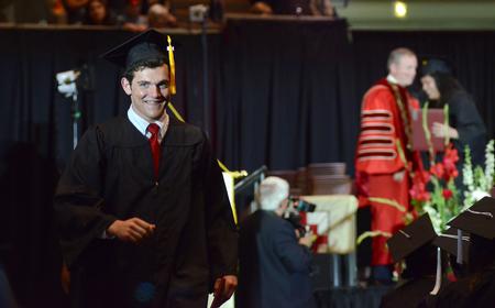 Ben Hall, bachelor of science political science graduate, walks back to his seat after receiving his diploma during spring graduation.  - Photo by MiKalla Cotton
