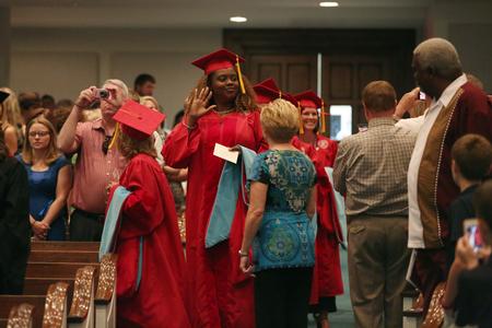 Gerlonda Hardin, doctor of education graduate, waves to friends and family in the audience during the processional at Summer Graduation. - Photo by Kristi McMurry Woody