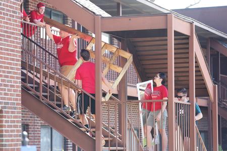Student leaders carry furniture upstairs to a new student's room on move-in day. - Photo by Kristi McMurry Woody