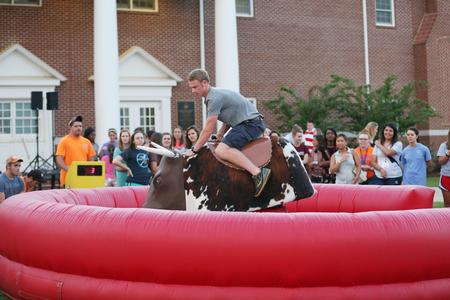 Students enjoy the mechanical bull ride, one of several inflatable games at the SAC Welcome Week Fest outside the Bowld Student Commons. - Photo by Kristi McMurry Woody