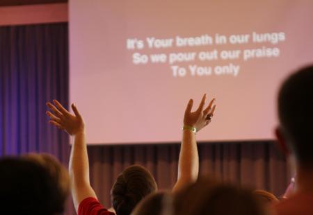 A student raises her hands in praise during chapel worship service. - Photo by Sol Bee Park