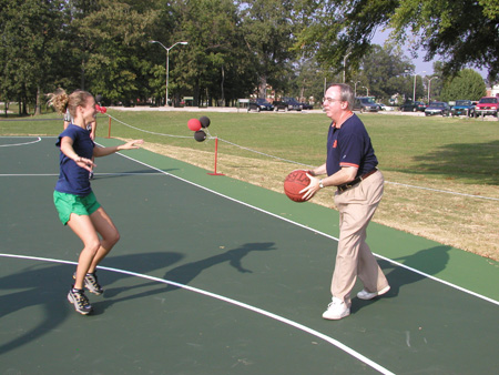 President David S. Dockery squares up for a three pointer against student Rachel Lovelace at the Faculty/Staff vs. Student game at the dedication of the Class of 2002 Basketball Court. - Photo by Cam Tracy