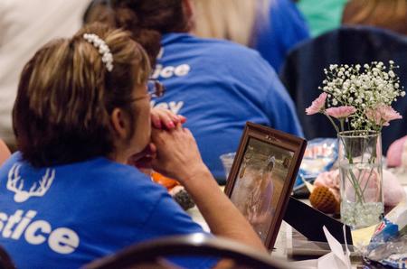 A participant in the Remember Me Walk sits with a photo of her loved one, listening as speakers dedicate uplifting words to others lost to homicide in the Carl Grant Events Center. - Photo by David Parks