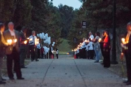 The pathway along the Great Lawn is lined with students and faculty bearing candles, awaiting homicide victims’ family members to pass through during the Remember Me Walk. - Photo by David Parks