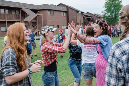 Covered in fake tattoos, residence adviser Erin Slater high-fives students after a victory in the annual DF Olympics on the Heritage Complex lawn. - Photo by David Parks
