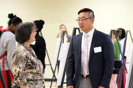 Jonathan Suh, senior social work major, talks about his poster to Mary Anne Poe, professor of social work, at the Fall Poster Session held in the Bowld Commons gym.  - Photo by Sol Bee Park