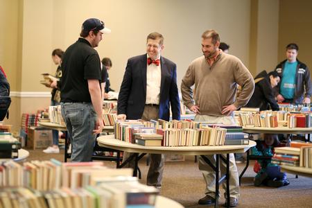Ray Van Neste (center), director of the R.C. Ryan Center for Biblical Studies, talks with guests of the huge book sale hosted by the Ryan Center and held in the Grant Center. - Photo by Kristi McMurry Woody