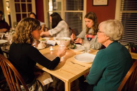 Beth Adams, junior English and history major, talks with Nancy Thomas, associate director of the center for faculty development, over a meal at the Thomas home during Be Our Guest. - Photo by Kristi McMurry Woody