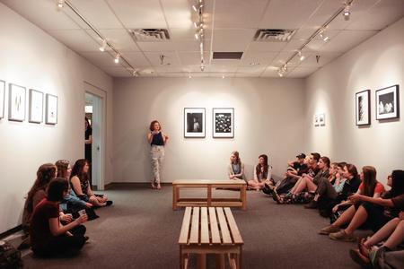 Students meet in the art gallery to see and hear about the work of photographer and alumna Lily Glass during her art reception.  - Photo by David Parks