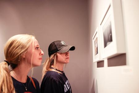 Madison Borden, freshman exercise science/wellness major, and Hope Magee, freshman art major, look at the photography work of Lily Glass during her art reception. - Photo by David Parks