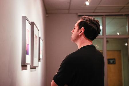 Joe Garner examines the fine art photography of Lily Glass in the art gallery. - Photo by David Parks