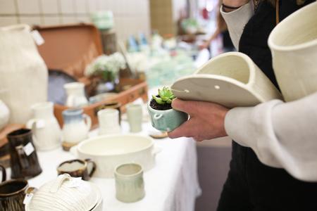 Guests gather pieces of student pottery at the annual Mother's Day Pottery Sale.  - Photo by Kristi McMurry Woody