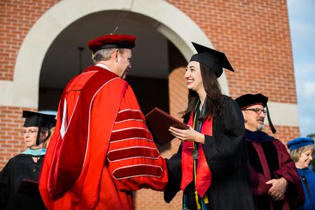 Anna Goodman, communication studies graduate, receives her diploma during spring commencement services on the Great Lawn. - Photo by Kristi McMurry Woody