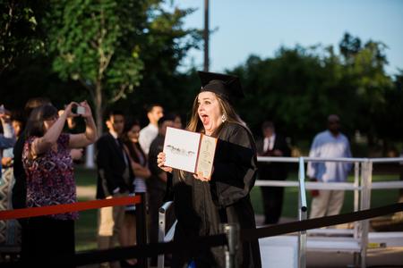 Music graduate Anna Marie Cox celebrates with her diploma as she sees friends and family at the spring commencement ceremonies. - Photo by Kristi McMurry Woody