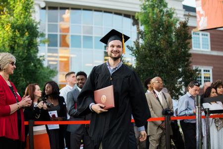 Victor Miller, digital media studies graduate, walks back to his seat after receiving his diploma at spring commencement services.  - Photo by Kristi McMurry Woody