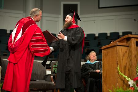 Alan Kruer, master of Christian studies graduate, receives his diploma from Dub Oliver, president of the university, during Summer Commencement. - Photo by Kristi McMurry Woody
