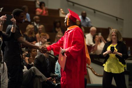 Oluwapelumi Ogunyemi, doctor of nursing practice graduate, shakes hands with a friend after receiving his diploma at Summer Commencement. - Photo by Kristi McMurry Woody