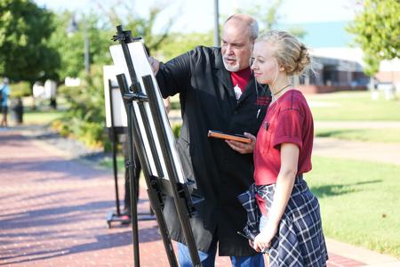 Chris Nadaskay, university professor of art, teaches a drawing class outside and demonstrates a technique for Madison Borden, sophomore exercise science/wellness major. - Photo by Kristi McMurry Woody