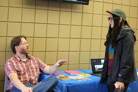 Steve Halla, assistant professor of art, talks with Song Kim, senior art studio major, at the Study Abroad Fair.  - Photo by Kristi McMurry Woody