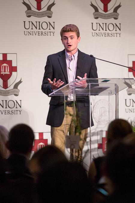 Caleb Scarbrough, senior teaching and learning major, welcomes guests to the Union Auxiliary banquet and introduces keynote speaker David Boudia. - Photo by Kristi McMurry Woody