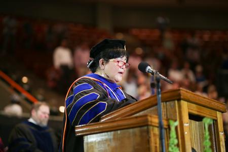 Lunawati Bennett, associate professor of pharmaceutical sciences, prays at the beginning of the undergraduate spring commencement. - Photo by Kristi McMurry Woody